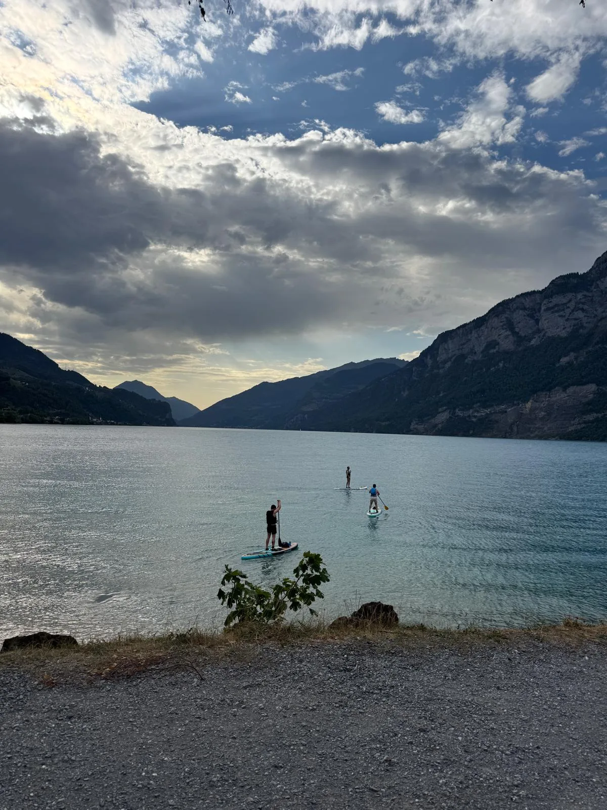 Drei Paddler gleiten hinaus in die Abendruhe des Walensees